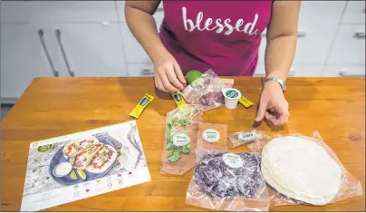  ?? CP PHOTO ?? Jayne Zhu lays out ingredient­s along side an instructio­n card before preparing a Hello Fresh cajun fish tacos meal kit, at her home in Vancouver, B.C., on Dec. 6. Home-delivered meal kits have quickly grown into a $120-million industry in Canada, according to analysts.