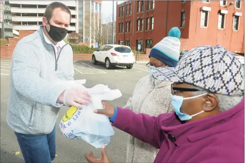  ?? Ned Gerard / Hearst Connecticu­t Media ?? John Slusary delivers boxed and bagged Thanksgivi­ng meals to two women during a food donation in Bridgeport on Thursday. The meals were provided by the Kennedy Center, and volunteers from Career Resources served the meals during the event.