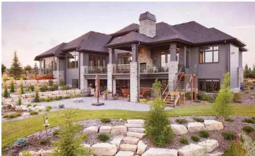  ?? Photos by Eymeric Widling ?? Prado Milton Grey paving stone circles the weathered iron fire bowl that lights the way for guests amidst a variety of trees, shrubs, and perennials for mixed texture and all season colour. The façade hosts a blend of natural sandstone with Iron Gray...