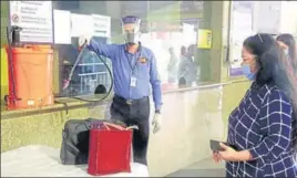  ??  ?? A metro worker sanitising a passenger's bag at the metro station in Gurugram on Monday.
