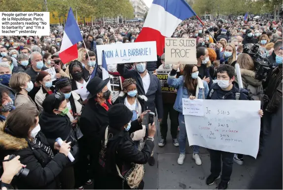  ??  ?? People gather on Place de la République, Paris, with posters reading “No to barbarity” and “I’m a teacher” yesterday