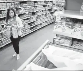  ?? Julio Cortez Associated Press ?? THE WAGE increase at Wal-Mart comes amid a tightening labor market and slashed corporate tax rates. Above, a Wal-Mart employee at a New Jersey store.