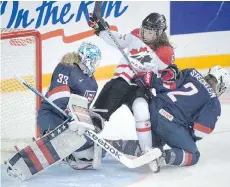  ?? RYAN REMIORZ/THE CANADIAN PRESS ?? Team Canada’s Rebecca Johnston is sandwiched between Team USA goaltender Alex Rigsby and Lee Stecklein at the women’s world hockey championsh­ips Monday in Kamloops.