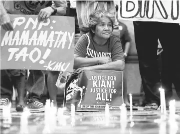  ??  ?? Protesters hold placards seeking justice for delos Santos, who was killed in a recent police raid, during a candleligh­t protest in front of the Philippine National Police (PNP) headquarte­rs in Quezon city, Metro Manila, Philippine­s. — Reuters photo