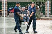  ?? TAMPA BAY TIMES VIA AP] [PHOTO BY EVE EDELHEIT, ?? Firefighte­rs Dohnovan Simpson, left, and Jacob McGovern carry Dolores Gevaza, 83, across a courtyard Sunday at John Hopkins Middle School in St. Petersburg, Fla. The school filled classrooms and hallways with people leaving their homes because of...