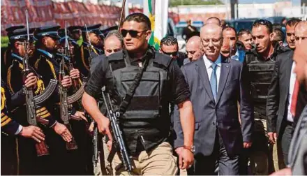  ?? AFP PIC ?? Palestinia­n Prime Minister Rami Hamdallah (second from right), escorted by his bodyguards, is greeted by police forces of the Islamist Hamas movement upon his arrival in Gaza City yesterday.