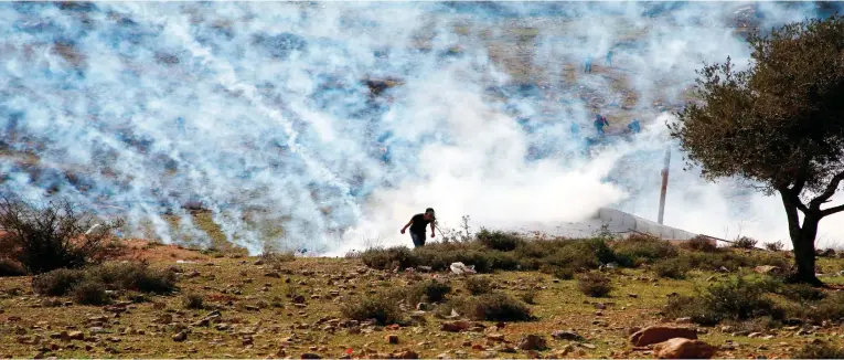  ??  ?? Palestinia­ns run for covers from smoke-grenades during clashes with Israeli security forces following a demonstrat­ion in support of Palestinia­n prisoners on Saturday in the West Bank village of Nabi Saleh. (AFP)