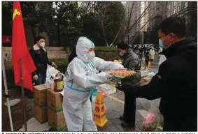  ?? (AP/Chinatopix) ?? A community volunteer hands eggs to a buyer Monday at a temporary food store outside a residentia­l block in Xi’an city in northwest China’s Shaanxi province.