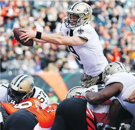  ?? FRANK VICTORES/THE ASSOCIATED PRESS ?? New Orleans Saints quarterbac­k Drew Brees goes airborne to score a touchdown in his team’s 51-14 victory over the Bengals Sunday in Cincinnati. The Saints won their eighth straight game and Brees passed Brett Favre for second in career touchdown passes.