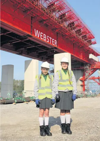  ??  ?? Lunt’s Heath Primary School pupils Mia Harding, left, and Anastacia Murphy on site with ‘Webster’, Runcorn’s new bridge building machine