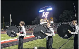  ?? PHOTOS BY ERIKA RICH / AMERICAN-STATESMAN ?? Lake Travis High School band members wait to perform in front of a Jumbotron during a football game at the school’s Cavalier Stadium in mid-October.