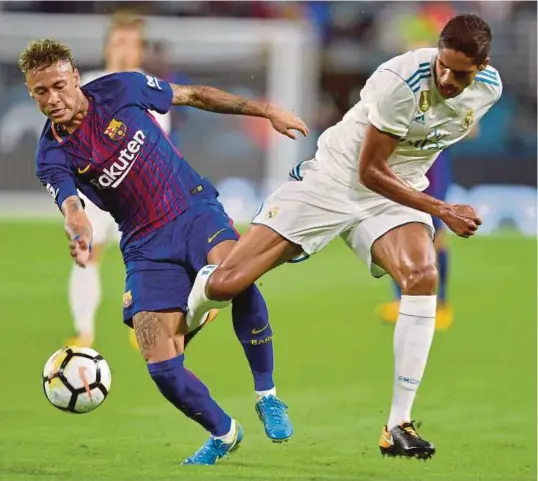  ??  ?? Neymar (kiri) diasak pertahanan Real Madrid, Raphael Varane pada aksi El Clasico di Florida, kelmarin.