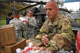  ?? JOE RAEDLE / GETTY IMAGES ?? Sgt. Angel Cotton and other members of the Puerto Rico National Guard deliver food and water via helicopter Friday to survivors of Hurricane Maria in Lares, Puerto Rico. The federal response to Puerto Rico’s crisis is being criticized.