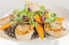  ??  ?? The pan-seared scallops are served with smoky bacon and lentil ragout.