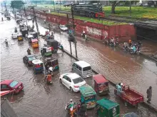  ?? AFP ?? Commuters make their way through a flooded street after ■
heavy monsoon rains in Lahore.