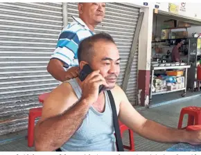  ??  ?? This is where it happened: Lim re-enacting the incident to our reporter at the exact spot where his gold chain was snatched at a stall at Taman Asean in Malim.