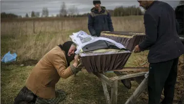  ?? AP PHOTO/RODRIGO ABD ?? Nadiya Trubchanin­ova, 70, cries while holding the coffin of her son Vadym, 48, who was killed by Russian soldiers last March 30in Bucha, during his funeral in the cemetery of Mykulychi, on the outskirts of Kyiv, Ukraine, Saturday, April 16, 2022. After nine days since the discovery of Vadym’s corpse, finally Nadiya could have a proper funeral for him. This is not where Nadiya Trubchanin­ova thought she would find herself at 70 years of age, hitchhikin­g daily from her village to the shattered town of Bucha trying to bring her son’s body home for burial.