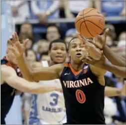  ?? GERRY BROOME — THE ASSOCIATED PRESS ?? North Carolina’s Theo Pinson, right, and Virginia’s Devon Hall (0) reach for the ball during the second half of an NCAA college basketball game in Chapel Hill, N.C., Saturday. North Carolina won 65-41.