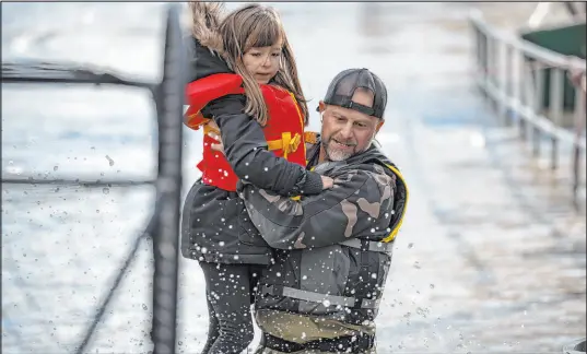  ?? Darryl Dyck The Associated Press ?? A volunteer carries a girl to high ground after using a boat to rescue a woman and children in Abbotsford, British Columbia.