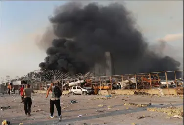  ??  ?? Port workers run to the scene of an explosion Tuesday at the seaport in Beirut. (AP/Hussein Malla)