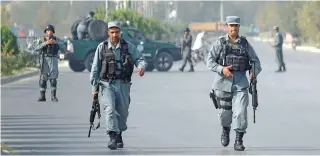  ?? - AFP ?? STRIFE-TORN: Afghan security personnel walks near the site following the militants’ raid that targeted the elite American University of Afghanista­n, in Kabul on Thursday. Taliban insurgents overran a district in eastern Afghanista­n, killing and...