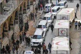  ?? AP ?? This photo released by the Syrian Red Crescent shows civilians gathering near a convoy of vehicles of the Syrian Red Crescent in Douma, eastern Ghouta, a suburb of Damascus on Monday. War-weary civilians are desperate for food and medical supplies.