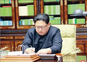  ?? AFP PHOTO/KCNA VIA KNS ?? This photo, released yesterday by North Korea’s official Korean Central News Agency, shows leader Kim Jongun signing an order of a test-fire of the interconti­nental ballistic rocket Hwasong-15.