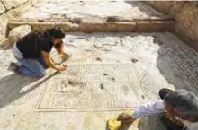  ??  ?? Timnah Goloubin, left, an archaeolog­ist with the Israel Antiquitie­s Authority, shows a church mosaic floor with inscriptio­n in ancient Greek.