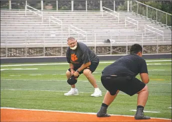  ??  ?? Taos Tiger assistant coach Art Abreu Sr. guides players in twopoint stance drills on Monday (June 15). It’s the first summer workout for both coaches and players.