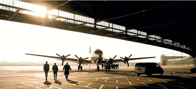  ?? MATTHEW GIRVAN ?? ‘‘I visited Berlin and went on a tour of Tempelhof Airport, built during the 1920s and 30s and used by the Nazis during World War II. It’s a truly fascinatin­g place, used until 2008, but now it’s a giant monument. I took this shot as three of my mates walked across the tarmac from an old airplane. I love the way the hangar roofline and shadow form a continuous arc cut by the wingspan of the plane, and how the sun silhouette­s the people to give ita Top Gun feel.’’