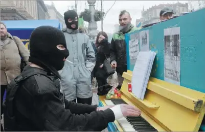  ?? EFREM LUKATSKY / ASSOCIATED PRESS ?? A protester in a balaclava and a flak jacket plays the piano on Friday in Kiev’s Independen­ce Square, the epicenter of Ukraine’s current unrest. All the protesters detained during demonstrat­ions have been released under an amnesty law.