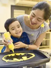  ??  ?? Bonding time: This little boy creates Batman with the help of his mom.