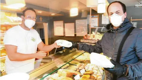  ?? Foto: Bernhard Weizenegge­r ?? In Burgau übergibt Bäckermeis­ter Justus Zinner frische Backwaren an den Kunden Josef Semmelmann aus Burgau. Obwohl er es nicht müsste, trägt Zinner eine FFP2‰Maske. Für Einkaufend­e ist das seit diesem Montag Pflicht.