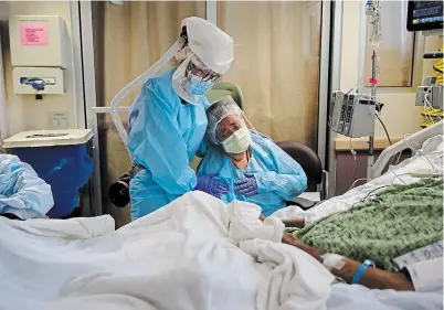 ?? JAE C. HONG THE ASSOCIATED PRESS FILE PHOTO ?? Nurse Michele Younkin comforts Romelia Navarro at the bedside of her dying husband, Antonio, in Fullerton, Calif., on July 31. The U.S. has less than five per cent of the globe’s population, but more than 20 per cent of the reported virus deaths.