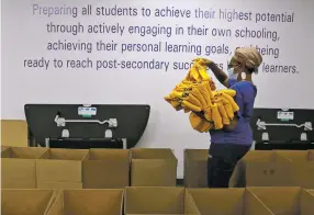  ?? JACQUELINE LARMA/ASSOCIATED PRESS ?? Stephanie Marshall, enrollment and marketing assistant at Agora Cyber Charter School in King of Prussia, Pa., fills boxes earlier this month with Agora supplies for family coaches to distribute to students. School officials say they got more money than they needed.