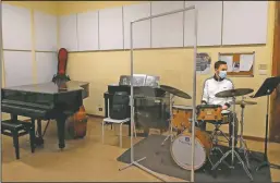  ??  ?? Andrea Lopalo wears a mask and plays the drums behind a transparen­t panel during a lesson at the Giuseppe Verdi Music Conservato­ry.