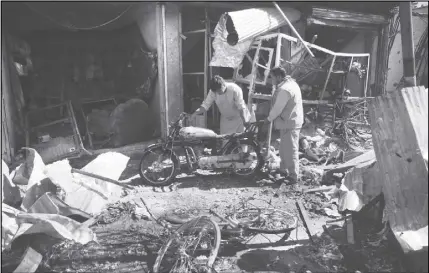  ??  ?? Men look at the remains of their properties at the site of a suicide attack in Kabul, Afghanista­n. A suicide car bomb killed dozens of people as well as the bomber early Monday morning in a western neighborho­od of Afghanista­n’s capital where several...