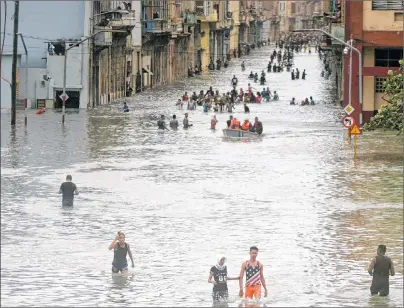  ?? AP PHOTO ?? People walk through flooded streets in Havana after the passage of hurricane Irma, in Cuba, Sunday. The powerful storm ripped roofs off houses, collapsed buildings and flooded hundreds of miles of coastline after cutting a trail of destructio­n across...