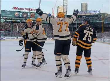  ?? MATT STONE — BOSTON HERALD ?? BOSTON, MA - January 2: Jeff Carter #77 of the Pittsburgh Penguins raises his arms in celebratio­n of Kasperi Kapanen #42 goal along with Danton Heinen #43 as Connor Clifton #75 of the Boston Bruins looks off during the second period of the Winter Classic at Fenway Park on January 2, 2023 in Boston, Massachuse­tts.