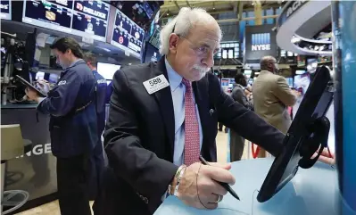  ??  ?? NEW YORK: Trader Peter Tuchman, right, works on the floor of the New York Stock Exchange. —AP