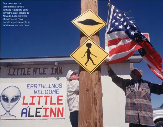  ??  ?? Dos hombres izan una bandera junto a llamada Autopista Extraterre­stre, en el estado de Nevada. Esta carretera atraviesa una zona donde supuestame­nte se avistan numerosos ovnis.