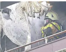  ?? ?? Ein Feuerwehrm­ann bei den Löscharbei­ten auf dem Balkon. Zu sehen ist er hier an geschmolze­nen Kunststoff­teilen.