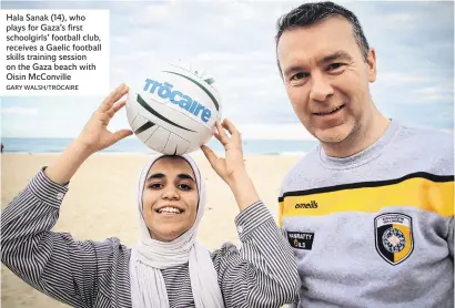  ?? GARY WALSH/TRÓCAIRE ?? Hala Sanak (14), who plays for Gaza’s first schoolgirl­s’ football club, receives a Gaelic football skills training session on the Gaza beach with Oisin McConville