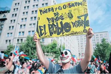  ??  ?? Un manifestan­te muestra un cartel contra el presidente Sebastián Piñera durante una protesta frente al Palacio de La Moneda.
JORNADA.