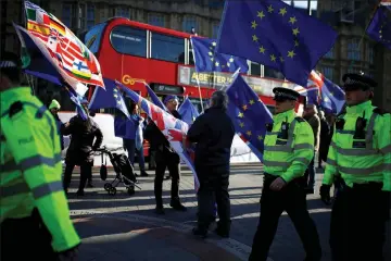  ??  ?? Police of cers walk past anti-Brexit demonstrat­ors outside the Houses of Parliament in London, Britain. — Reuters photos