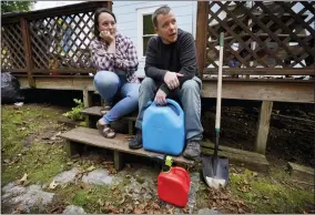  ?? AP PHOTO/ROBERT F. BUKATY ?? Lucinda Tyler and Aaron Raymo sit outside their home Oct. 5 with fuel containers they used to fill their heating oil tank at their home in Jay, Maine.