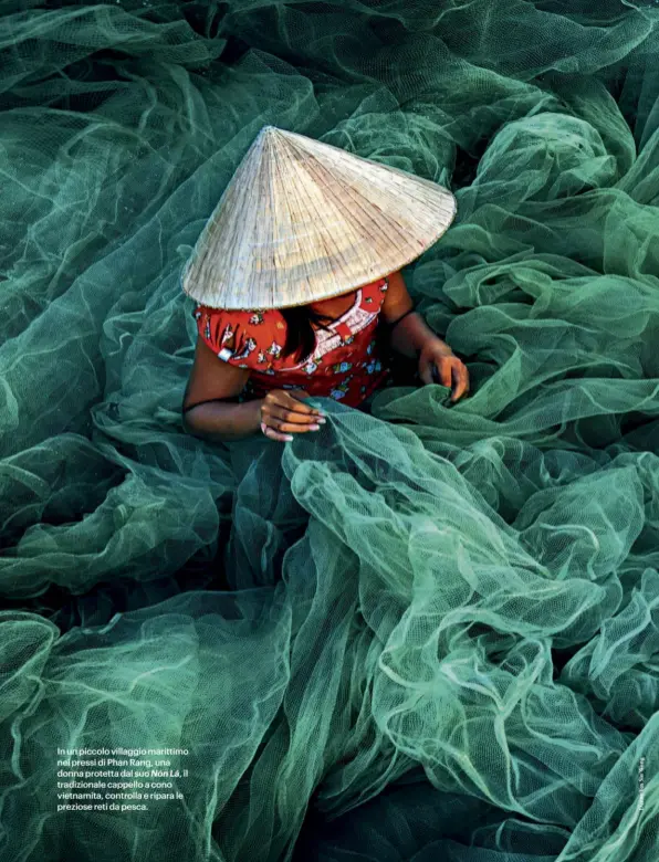  ??  ?? In un piccolo villaggio marittimo nei pressi di Phan Rang, una donna protetta dal suo Nón Lá, il tradiziona­le cappello a cono vietnamita, controlla e ripara le preziose reti da pesca.