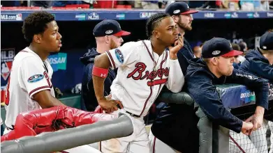  ?? CURTIS COMPTON / CCOMPTON@AJC.COM ?? The Atlanta Braves, including Ronald Acuna (left) and Ozzie Albies (center), watch dejectedly from the dugout while the Los Angeles Dodgers celebrate their Game 4 victory, giving a bitter ending to their National League Division Series and the Braves’ 2018 season.