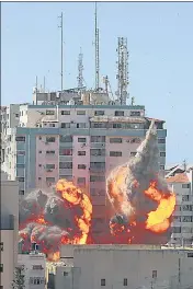  ??  ?? An explosion is seen near a tower housing AP, Al Jazeera offices (centre) during Israeli missile strikes in Gaza city.