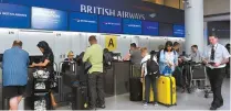  ?? Reuters-Yonhap ?? People wait with their luggage at the British Airways check-in desk at Gatwick Airport in southern England, Sunday.